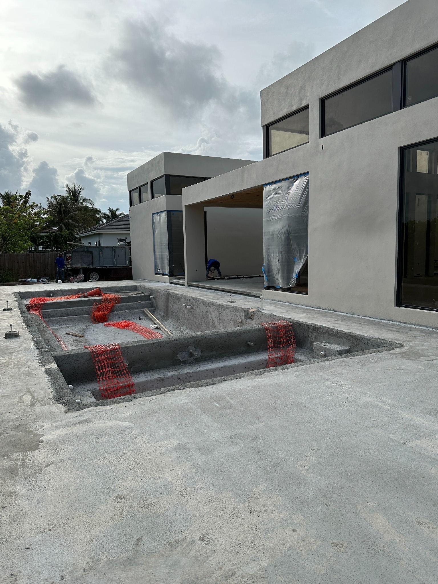 Custom pool shell beside a modern home under construction